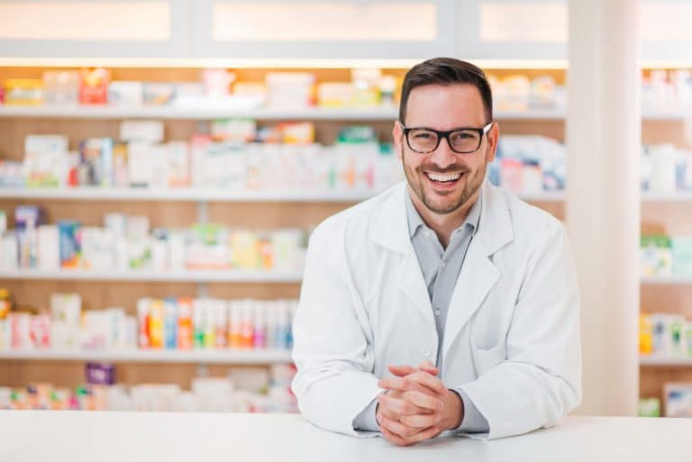 portrait-cheerful-handsome-pharmacist-leaning-counter-drugstore